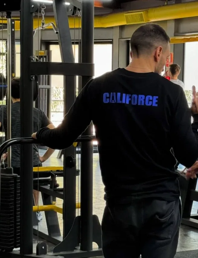 Profe de Califorce de espaldas, mirando la sala de musculación