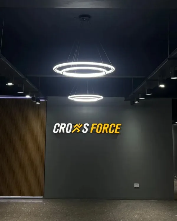 Nuevo piso: pared gris con el logo de Cross Force iluminado por dos lámparas circulares